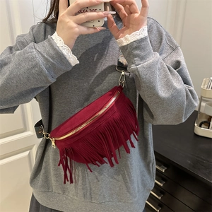 Sac à bandoulière bordeaux à franges avec sangle bohème porté par un mannequin