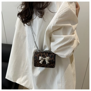 Détail d'un mini sac bandoulière léopard avec nœud argenté et bandoulière chaîne