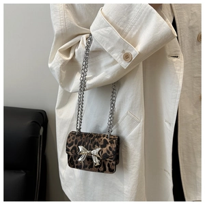 Détail du mini sac à chaîne léopard avec nœud en métal argenté et texture veloutée