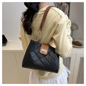 Détail du sac à bandoulière matelassé noir avec rabat marron et chaîne dorée