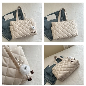 Detail view of beige quilted tote bag showing rhombus stitching and plush pendant charm