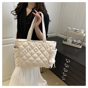 Quilted tote bag detail with plush charm and side pockets for minimalist styling