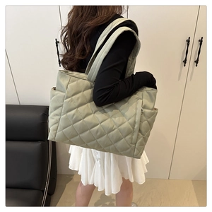Sage green quilted tote bag featuring classic diamond patterns and side storage pockets