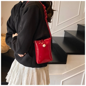 Détail du mini sac en cuir verni rouge avec fermoir perle et bandoulière chaîne