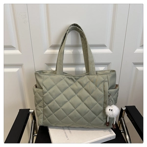 Quilted light green nylon tote bag with plush charm on a chair for daily commute