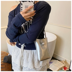 Gros plan d'un mini sac argenté avec un grand fermoir perle sur le rabat supérieur