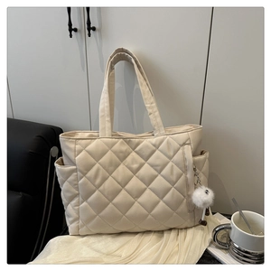 Detailed view of quilted tote bag with plush charm and convenient side pockets