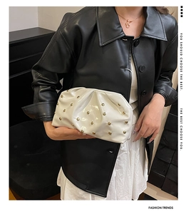 Détail d'une pochette nuage plissée blanche avec rivets champignons dorés et chaîne