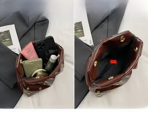 Détail du grand sac en cuir verni marron avec rivets dorés et intérieur spacieux