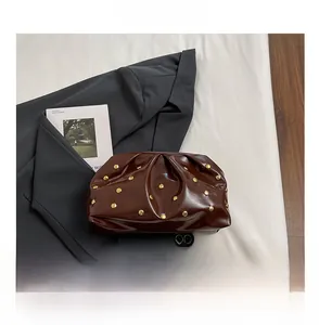 Détail du sac pochette plissé marron foncé avec clous dorés et comparaison de taille de téléphone