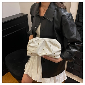 Détail du sac nuage plissé blanc avec rivets dorés porté par un mannequin en cuir