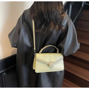 Détail du petit sac bandoulière vert clair en daim avec poignée porté sur une veste noire