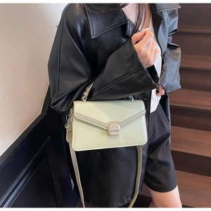 Détail du sac bandoulière en daim vert clair avec rabat enveloppe et boucle magnétique