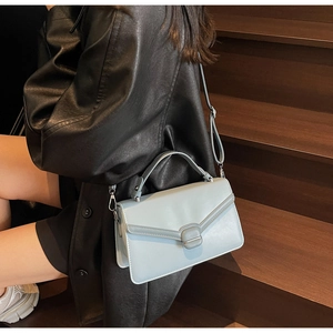 Vue détaillée d'un sac à bandoulière bleu clair avec rabat en V et boucle ronde