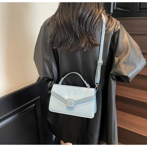 Vue détaillée du petit sac à bandoulière en daim bleu clair avec boucle carrée et poignée