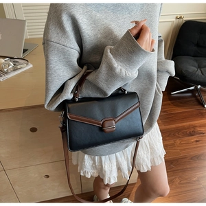 Détail du sac à bandoulière bicolore noir et marron en similicuir avec boucle métallique