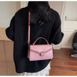 Détail du sac bandoulière rose en suédine avec rabat en V et boucle carrée ton sur ton