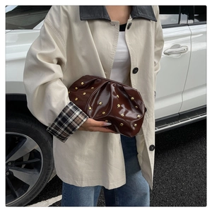 Gros plan sur un sac nuage en cuir brillant marron foncé avec des rivets dorés