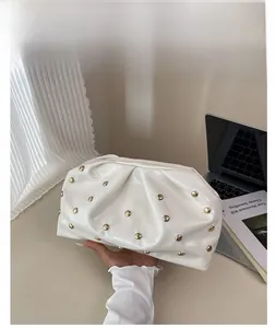 Vue détaillée du sac plissé blanc avec rivets métalliques dorés et design froncé