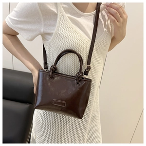Detail of dark brown tote bag in glossy oil wax finish with knotted handle design
