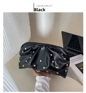 Détail de la pochette nuage noire avec rivets dorés et texture en cuir plissé brillant