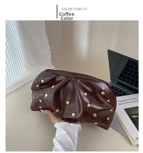Détail de la pochette plissée marron café avec des clous dorés et une texture en cuir