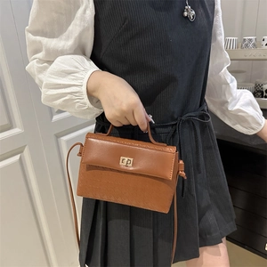 Caramel shoulder bag with houndstooth texture and gold turn-lock closure in hand