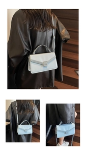 Detail of light blue crossbody bag with V-shaped stitching and tonal metal buckle