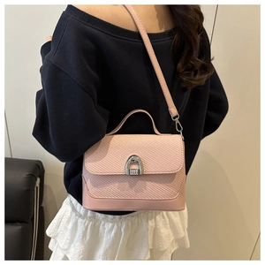 Side view of pale pink crossbody bag with woven texture and horseshoe metal lock