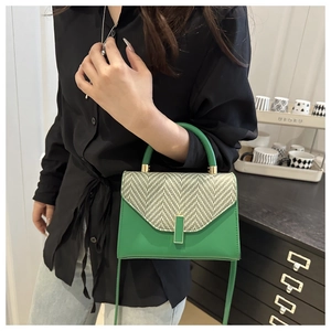 Close-up of green leather crossbody bag with woven herringbone texture flap and gold buckle