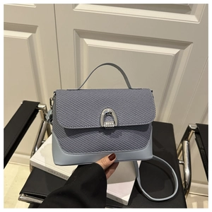 Detail of grey-blue woven handbag featuring a silver U-shaped clasp and leather strap
