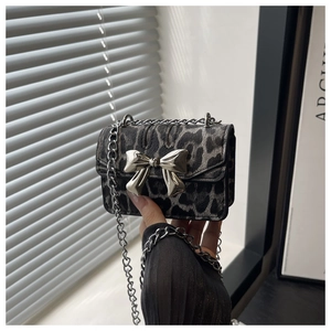 Detail of leopard print crossbody bag featuring a large silver metal bow buckle accent