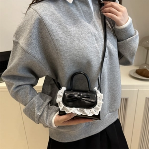 Mini black bow crossbody bag with white lace trim and adjustable shoulder strap