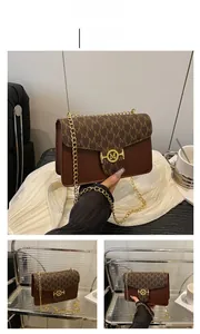 Detail view of brown crossbody bag featuring letter M pattern and gold metal buckle