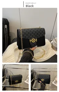 Close-up of black crossbody box bag with golden M-logo buckle and monogram print