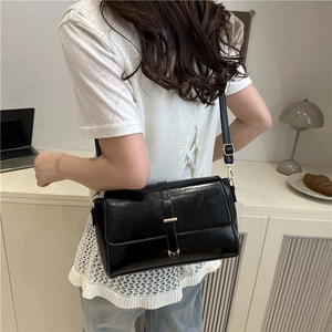 Borsa a tracolla nera lucida con dettaglio a cuore indossata da una modella elegante