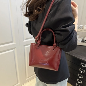 Glossy burgundy leather tote bag with top handles and adjustable strap for women
