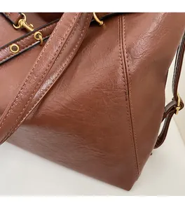 Detail of brown faux leather backpack with lychee texture and bronze metal hardware