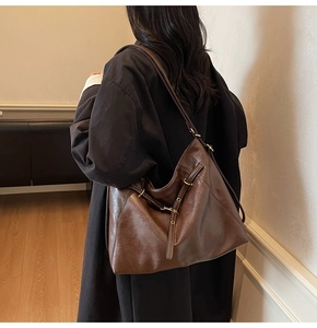 Detail of soft dark brown leather shoulder bag with metallic eyelets and strap decor