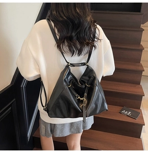 Detail of black matte leather backpack with golden metal buckles and adjustable straps
