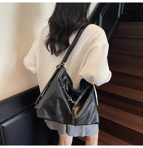 Detail of black oiled leather tote bag with gold hardware shown on model on stairs