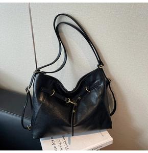 Detail of soft black leather texture and gold hardware on a large capacity hobo bag