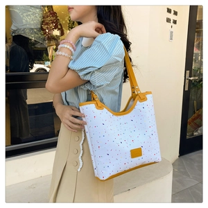 Outdoor lifestyle view of colorful polka dot canvas bucket bag with yellow leather straps