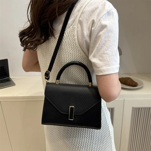 Minimalist black leather crossbody bag with embossed texture and gold metal buckle