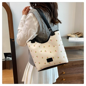 Detail of floral embroidery on cream leather tote with black contrast shoulder straps