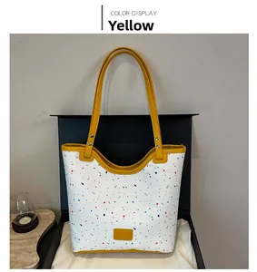 Detail of white tote bag with colorful ink splashes and yellow leather accents