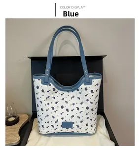 Detailed shot of a floral tote bag with blue trim and purple rose patterns in a gift box