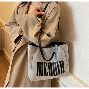 Close-up of the woven canvas tote bag featuring black MCROIA lettering and leather straps