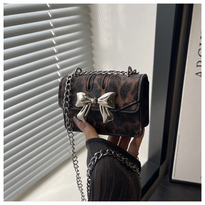 Close-up of leopard print mini bag featuring a silver metal bow buckle and chain strap