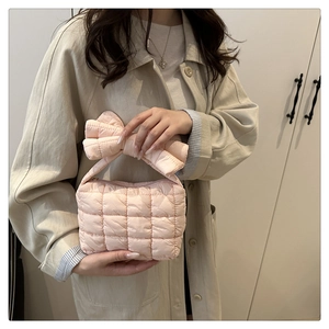 Model wearing a pink quilted handbag featuring a large puffy bow handle detail